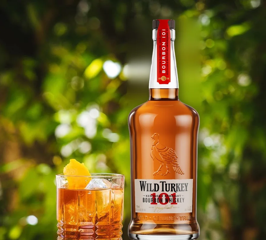 Drink com whisky Wild Turkey 101 em copo baixo, ao lado da garrafa